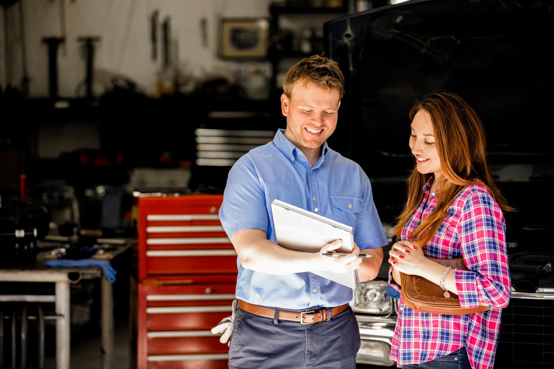 Happy customer discusses repairs with auto mechanic in repair shop.