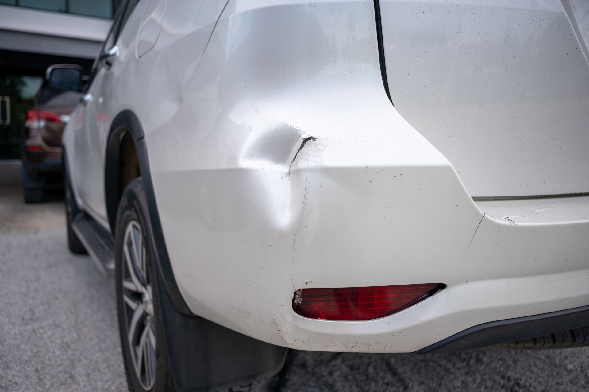 Car rear bumper with large dent and cracked paint