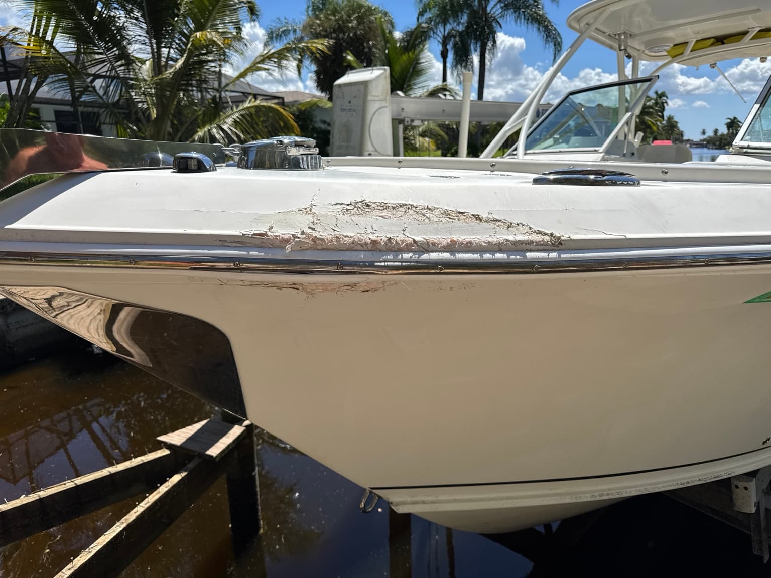 Close-up of gouged and chipped gelcoat above a boat rub rail